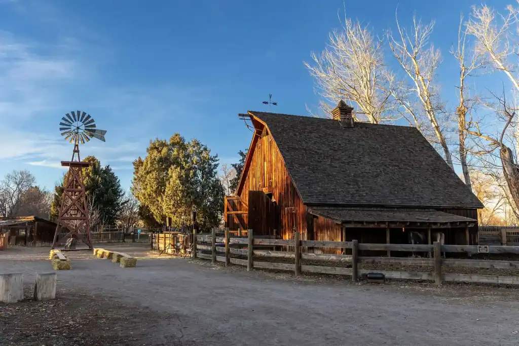 Historic wooden barn and windmill at Littleton Museum outdoor area.